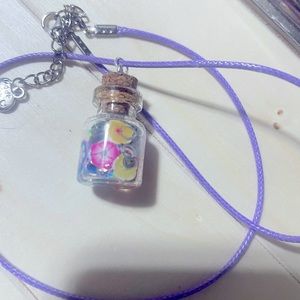 Cute bottle filled with flowers and silver glitter on a purple cord necklace